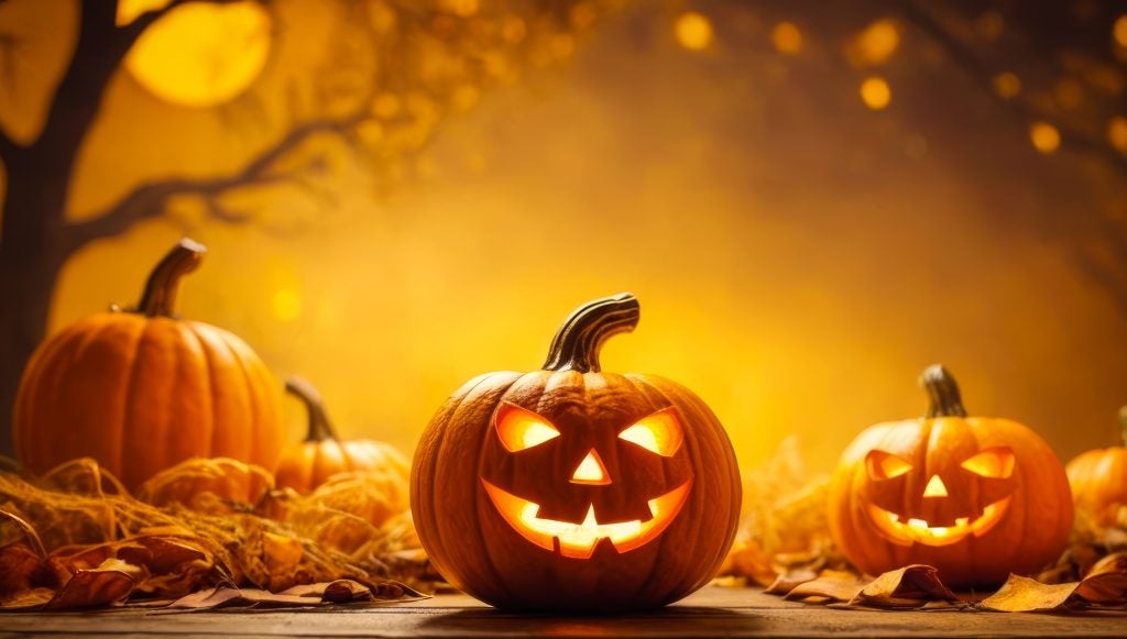 A Halloween setting with Jack-O-Lantern's, leafless trees, and the moon with an orange hue. - Boyd GM Oxford, NC