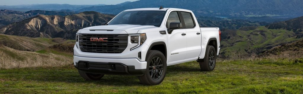 An all-new Summit White 2024 GMC Sierra 1500 parked on a pasture in front of the rolling hills of Oxford, NC.