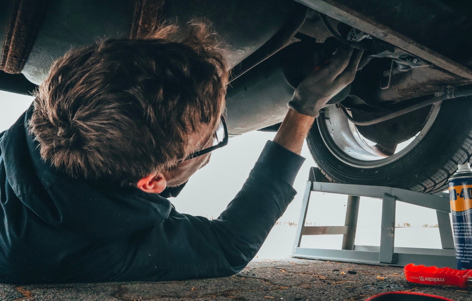 Man repairing a Chevy vehicle from underneath.