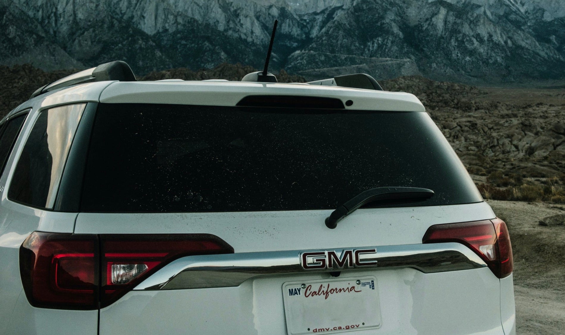 Back of a white GMC Crossover with overcast, night fall sweeping in.