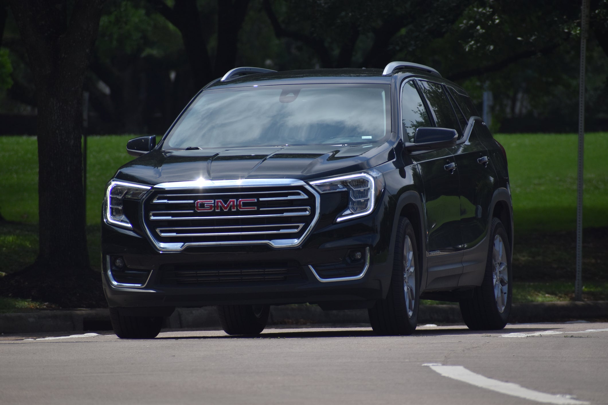 A portrait of a black GMC Terrain SUV near a nature reserve