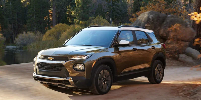 Brand new grey Chevrolet Trailblazer driving down a forest dirt road.