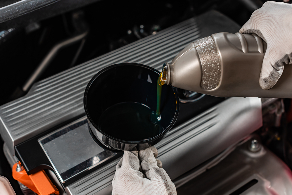 person pouring oil in a car