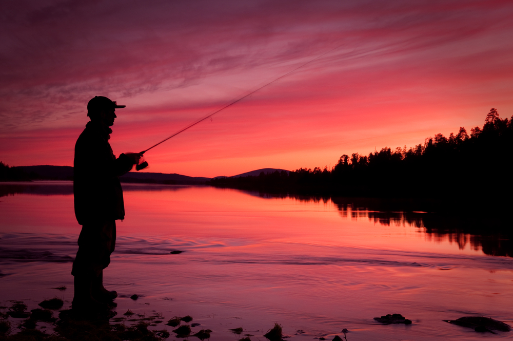 man silhouette fishing with sunset colors