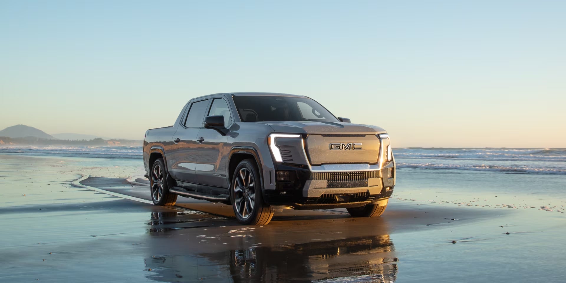 2025 GMC Sierra EV Denali driving on a wet sandy beach