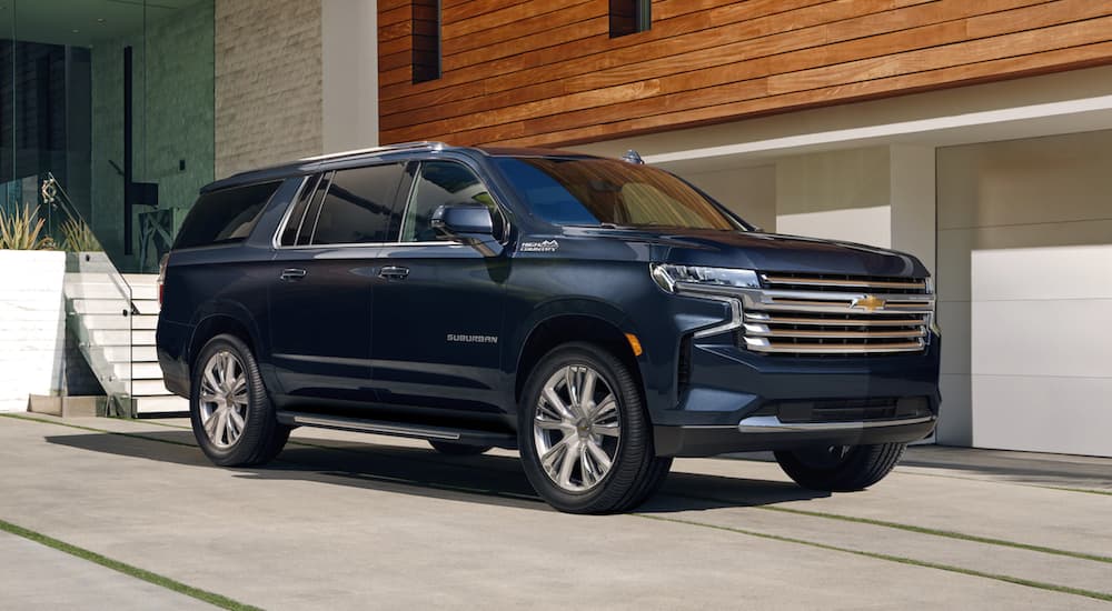 Black 2021 Chevy Suburban High Country parked in the driveway of a modern house.