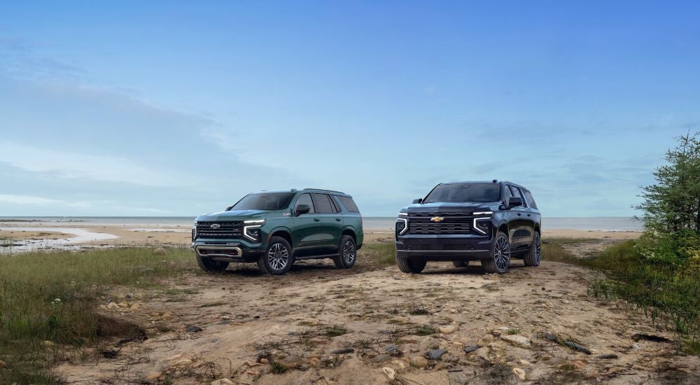Green 2025 Chevy Tahoe Z71 and blue 2025 Chevy Suburban High Country parked on a beach