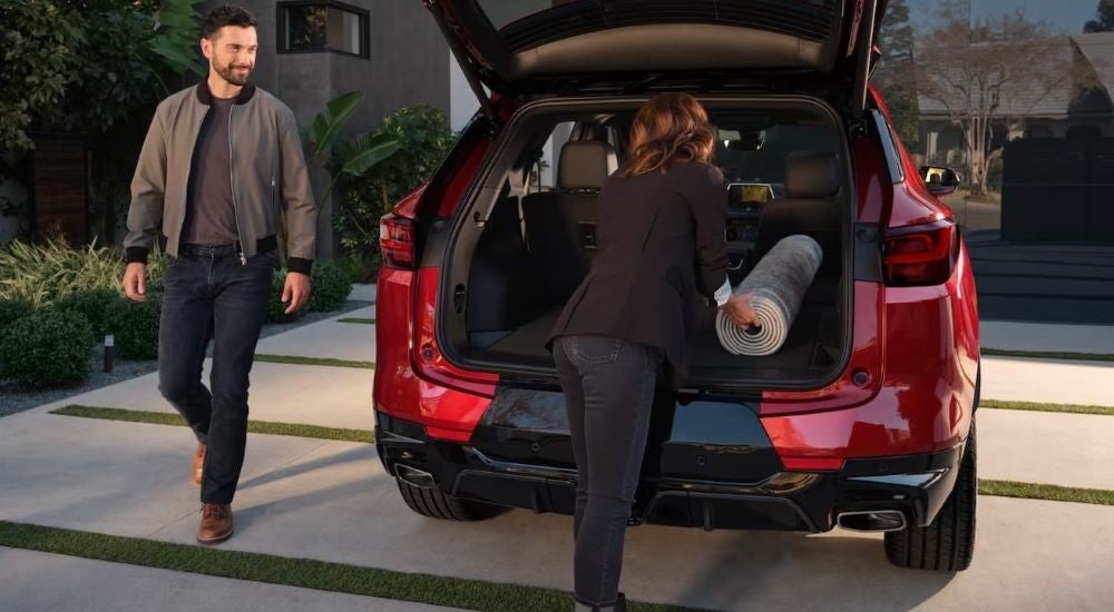 Woman loading a large rug into the back of a red 2024 Chevy Blazer