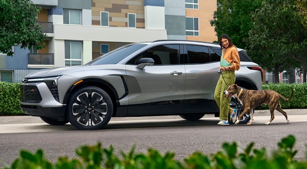 Woman walking by a parked grey 2025 Chevy Blazer EV