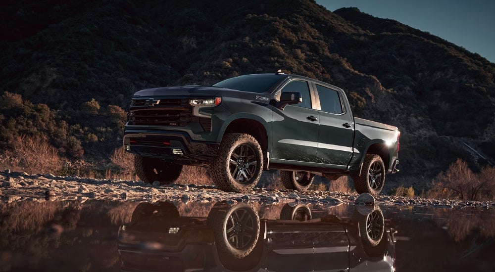 Dark green 2025 Chevy Silverado 1500 Trail Boss parked near a lake
