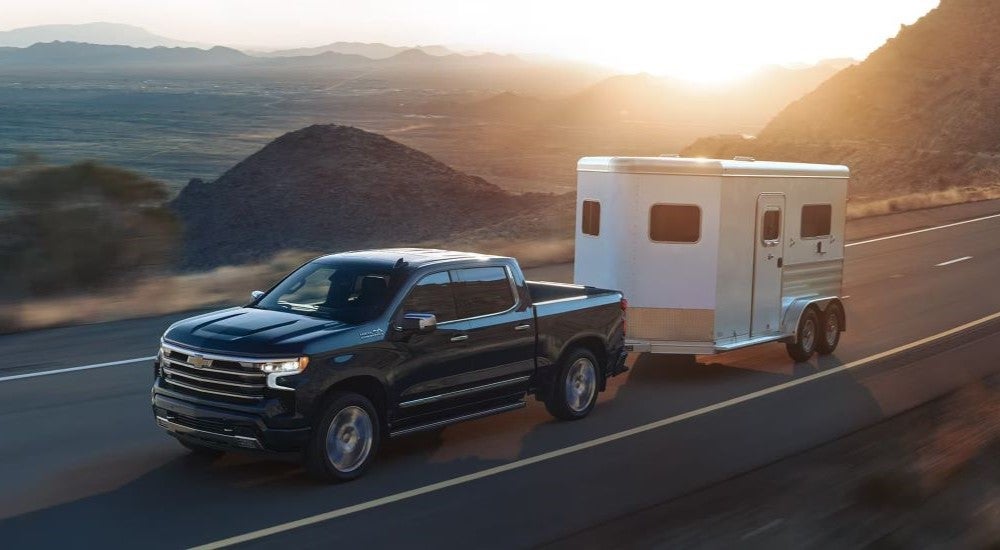 Black 2024 Chevy Silverado 1500 High Country towing a trailer