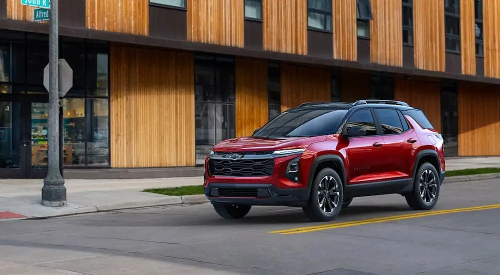 A red 2025 Chevy Equinox RS is stopped at an intersection during a test drive at a Chevy dealer.