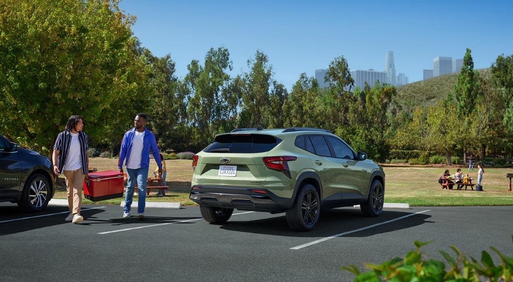 A green 2025 Chevy Trax ACTIV is shown parked near a picnic area.