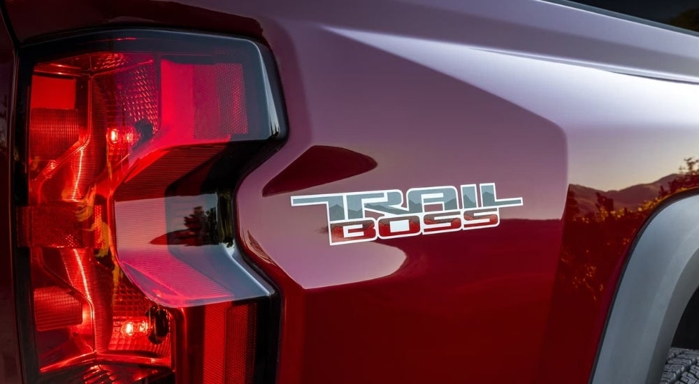 A close-up shows the Trail Boss decal on a red A red 2023 Chevy Colorado Trail Boss.