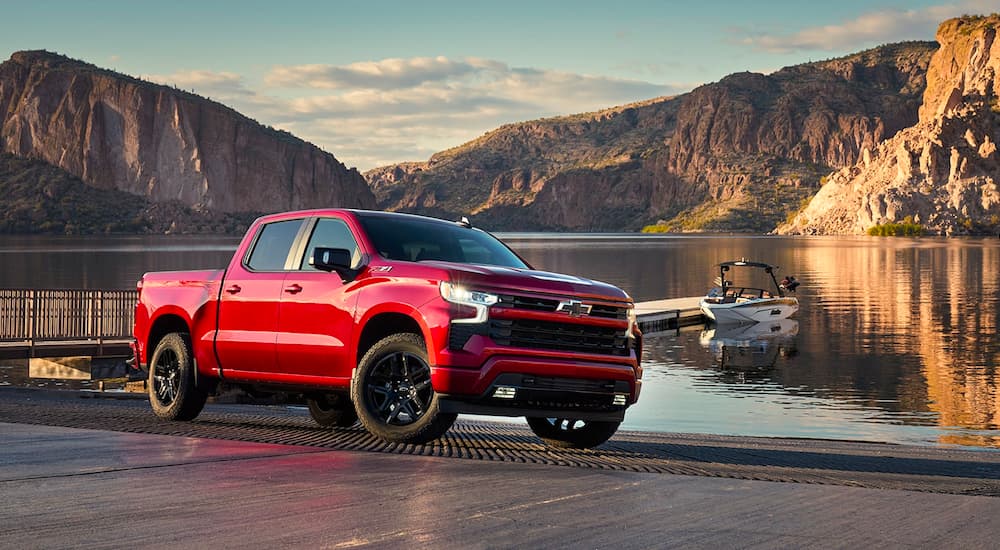 A red 2024 Chevy Silverado 1500 RST is shown parked near a lake after visiting a Chevy dealer near Iuka.