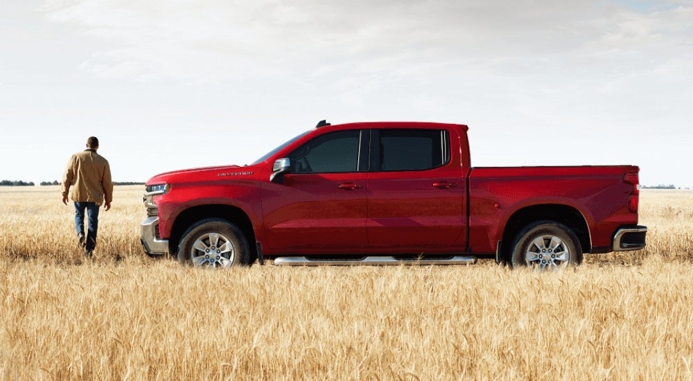 A red 2021 Chevy Silverado 1500 is shown parked on grass after leaving a Chevy dealer near you.