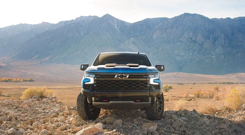 A popular used Chevy Silverado for sale, a blue 2024 Chevy Silverado 1500 ZR2, is shown parked off-road.