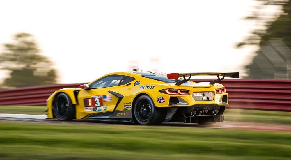 A yellow 2020 Chevy Corvette C8.R is shown driving on a racetrack.