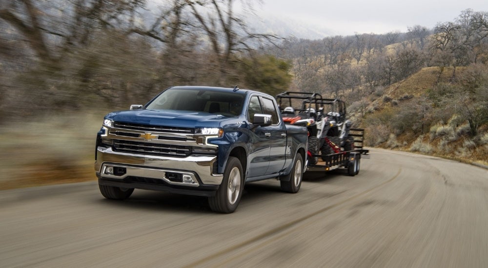 A dark blue 2020 Chevy Silverado 1500 is towing ATVs.