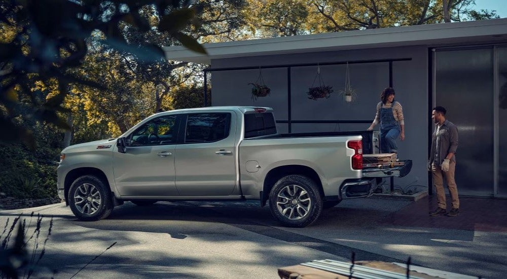 A silver 2024 Chevy Silverado 1500 Z71 is shown parked in front of a house.