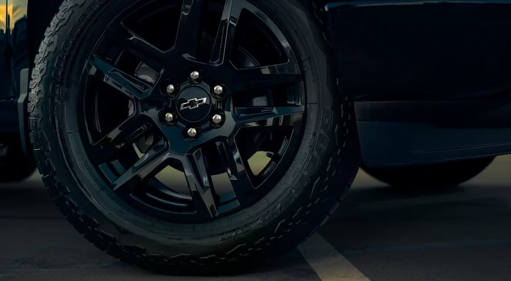 A close up of the black wheel and rim on a 2025 Chevy Silverado 1500 Custom.
