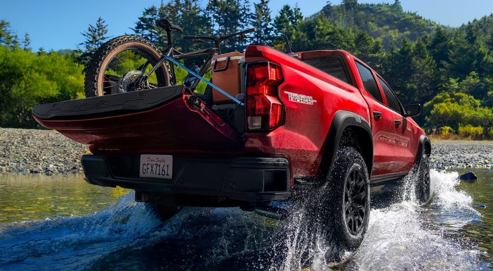 A red 2024 Chevy Colorado Trail Boss is shown splashing through a creek.