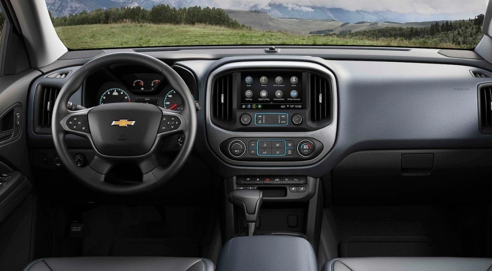 The black interior of a 2021 Chevy Colorado shows the steering wheel and infotainment screen.