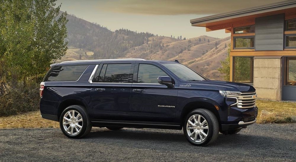 A dark blue 2024 Chevy Suburban High Country is shown in front of a house after leaving a Chevy dealer near Henderson.