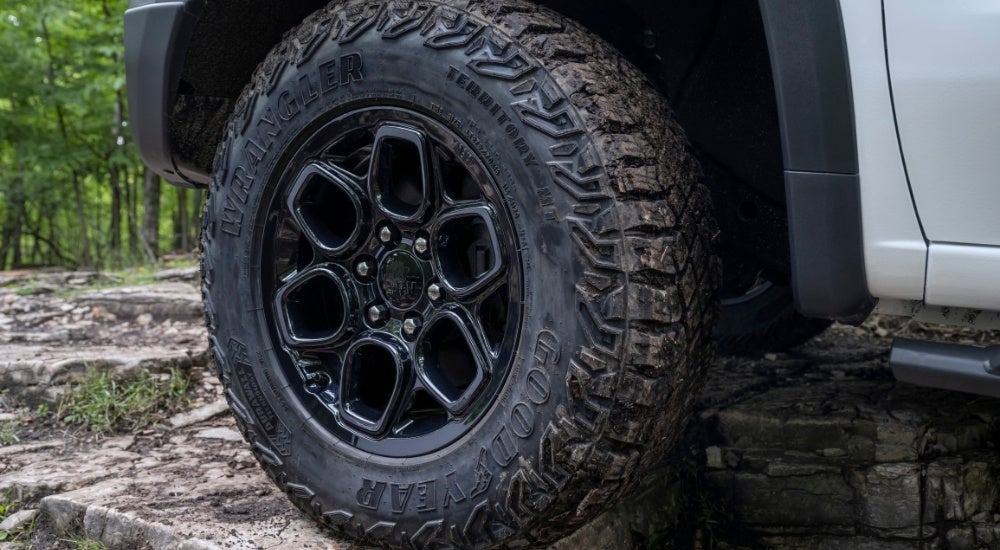 A close-up shows a wheel and tire on a white 2023 Chevy Silverado 1500 ZR2 Bison.