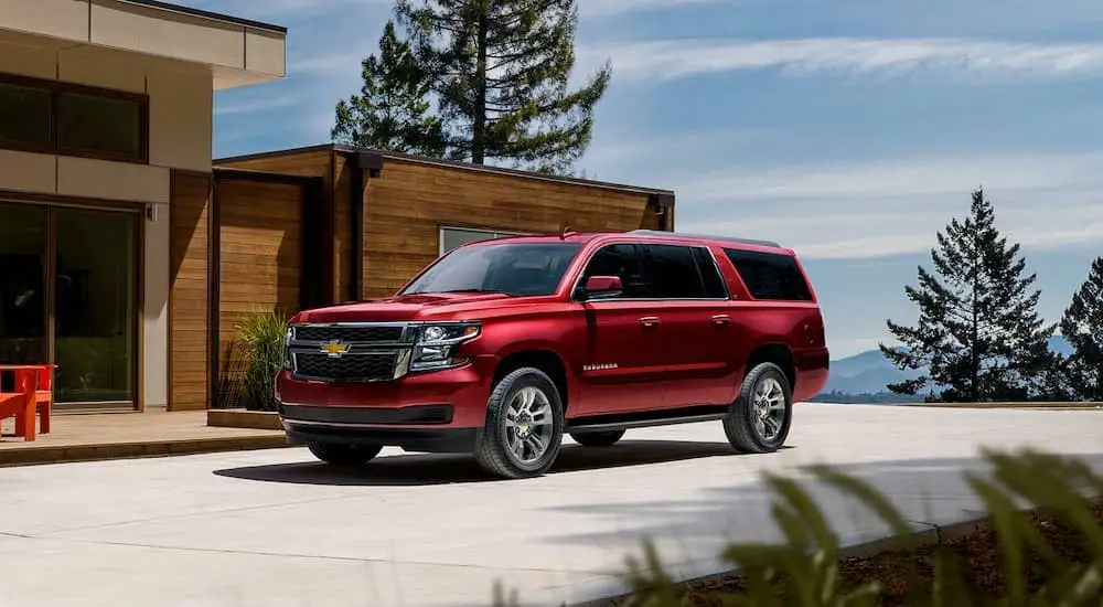 A red 2020 Chevy Suburban is shown parked outside of a modern home.