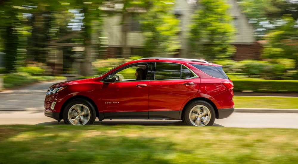 A red 2018 Chevy Equinox is shown driving near a house.