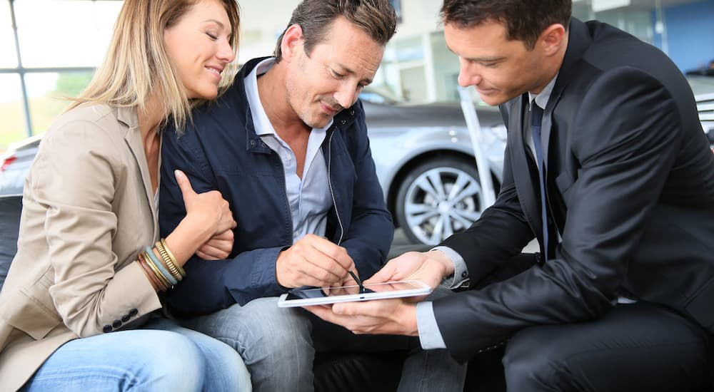 A couple is shown signing Chevy financing terms on a tablet.
