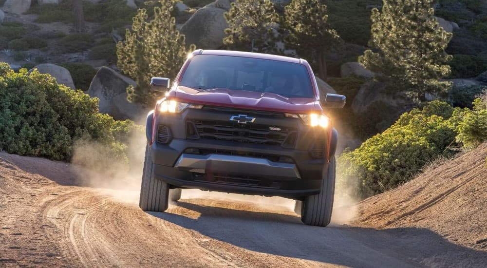 A red 2023 Chevy Colorado Trail Boss is shown from the front driving on a trail.