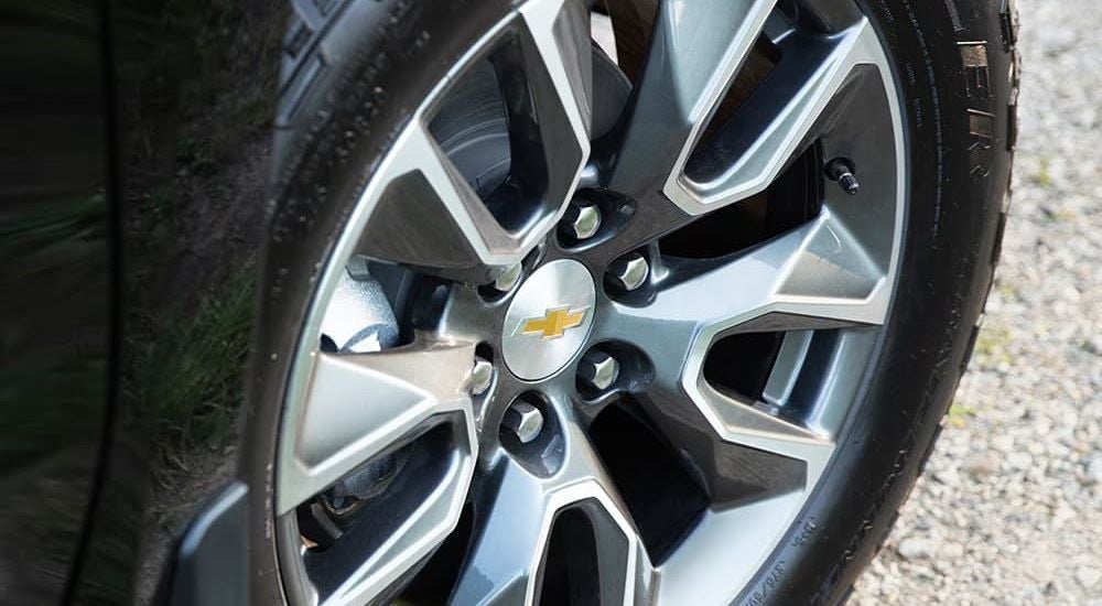 A silver wheel is shown on a black 2024 Chevy Silverado for sale in Corinth, MS.