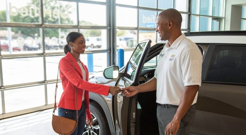 A person is being handed keys after obtaining Chevy financing.