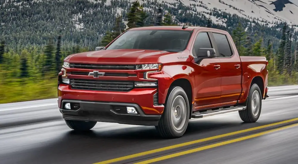 A red 2021 Chevy Silverado 1500 is shown driving on an open road.