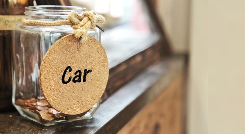 A close up shows a jar with car downpayment savings.
