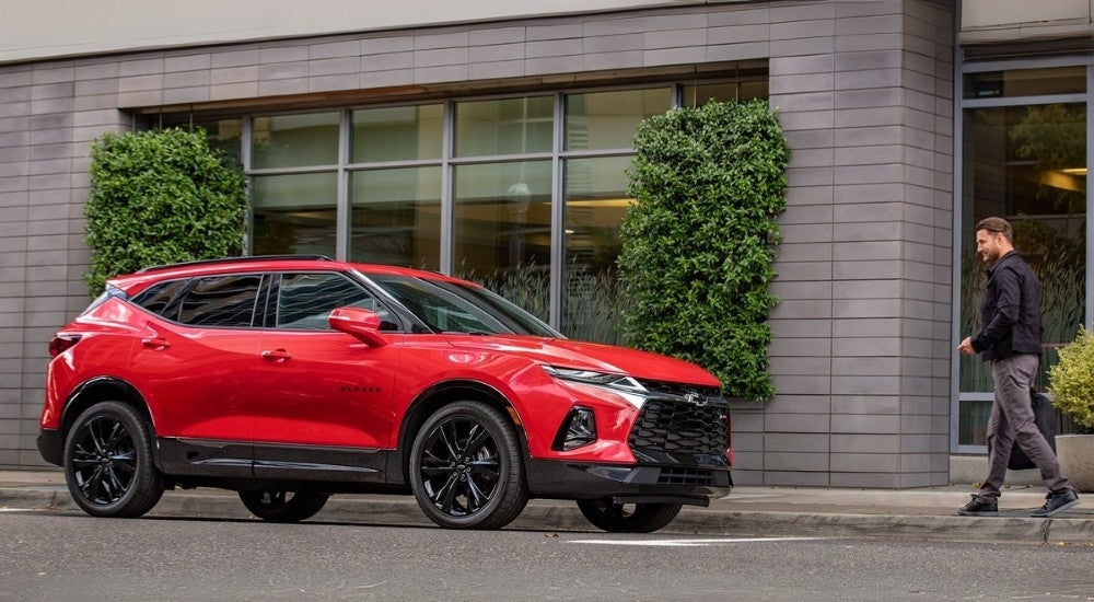 A person is shown approaching a red 2020 Chevy Blazer RS after looking at Chevy SUVs.