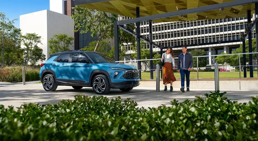 A blue 2025 Chevy Trailblazer RS is parked as a couple walks by.