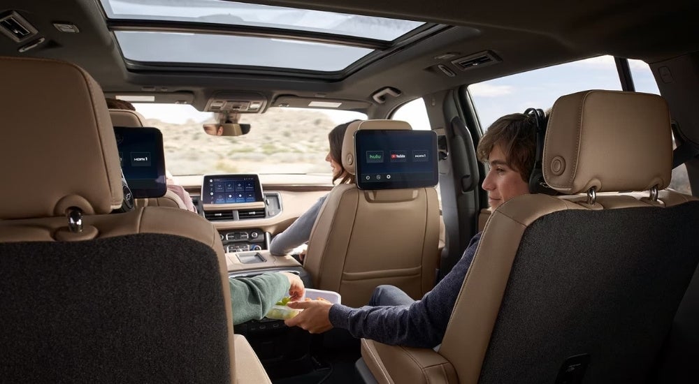A family on a roadtrip enjoying the entertainment screens in a 2024 Chevy Suburban Premier.