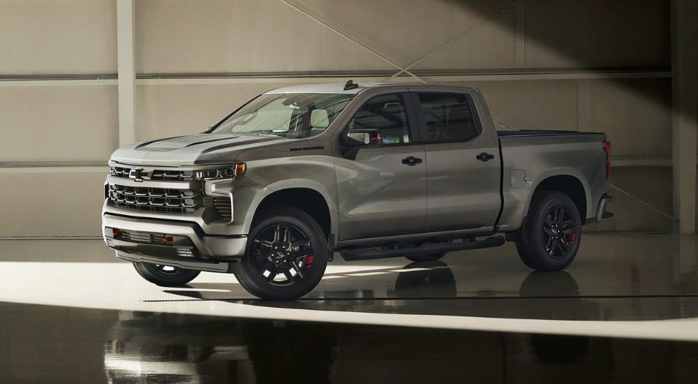 A silver 2024 Chevy Silverado 1500 Redline is shown in a warehouse after leaving a Chevy dealer.
