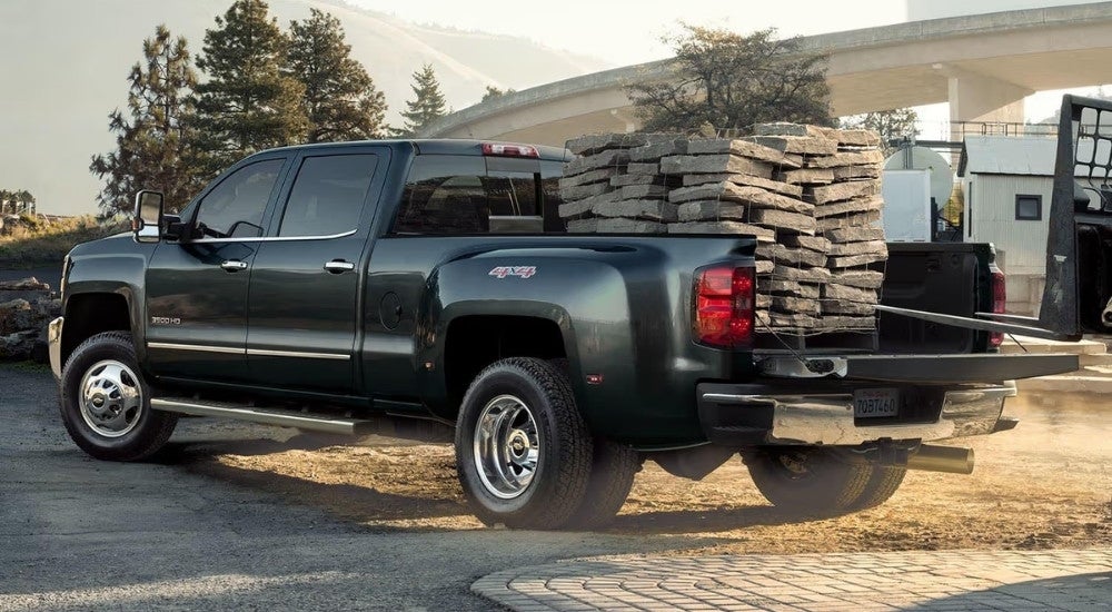 A black 2019 Chevy Silverado 3500 HD is parked with stone in the bed.
