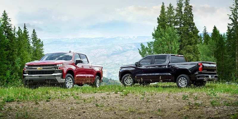 Red Chevy Silverado next to a black Chevrolet Silverado
