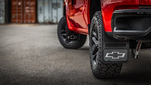 Close on rear left wheel of red Chevrolet Silverado 1500 with Chevy logo on tire flap