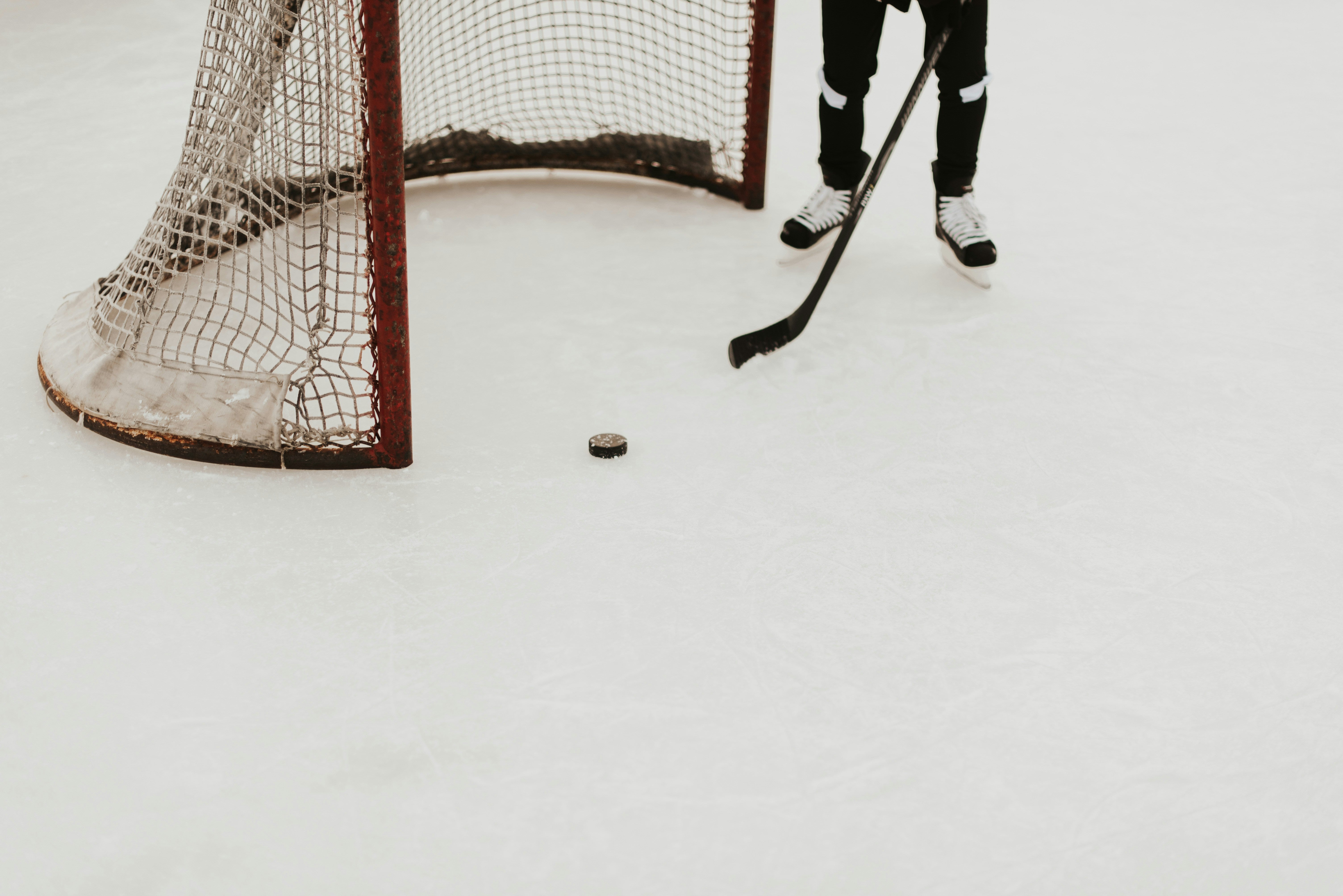 Skating at ice rink with hockey stick and puck in front of hockey goal