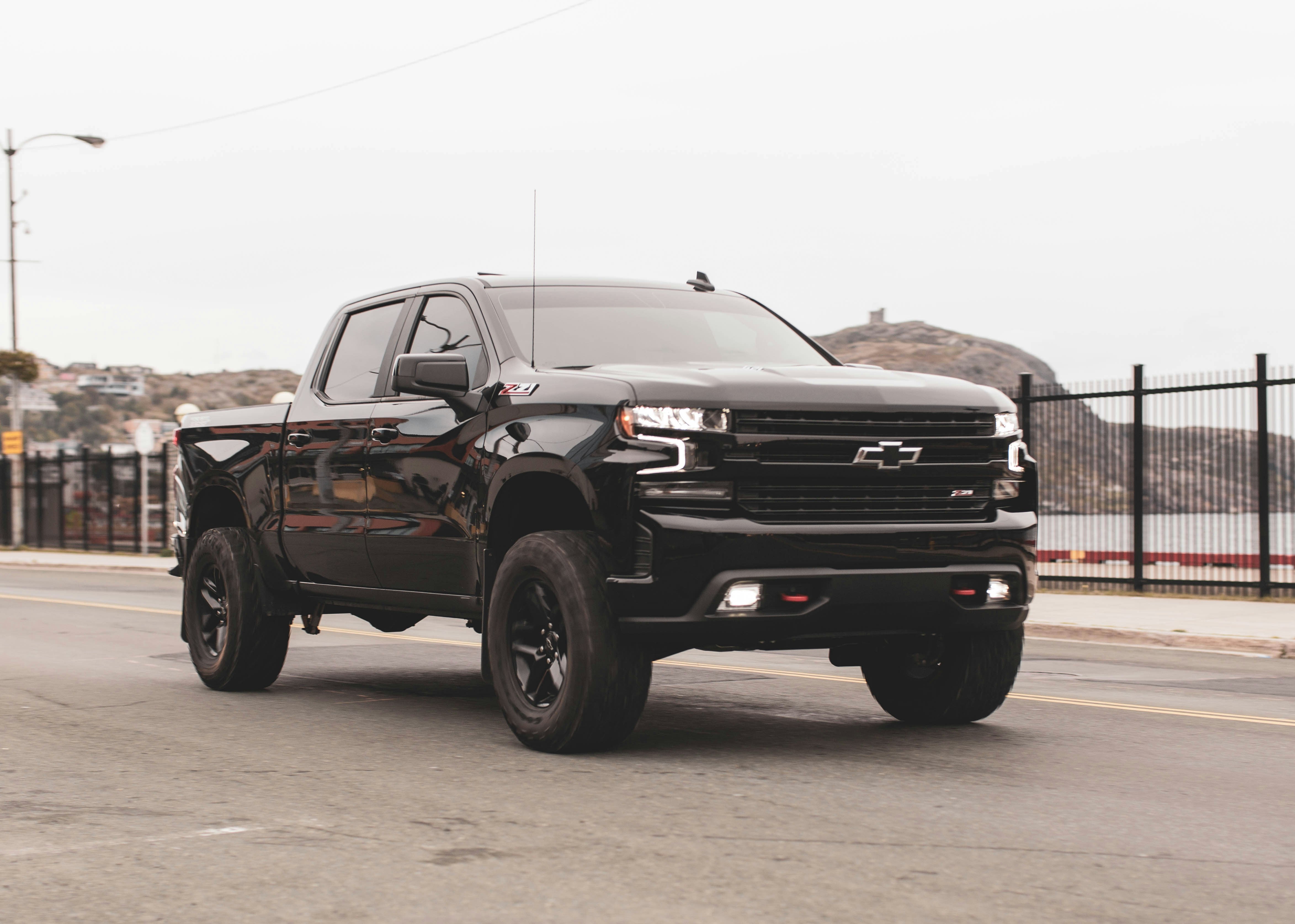 Black Chevy Silverado truck driving on empty road