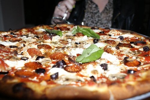 Handmade pepperoni pizza with olive, mushrooms, and basil at low angle