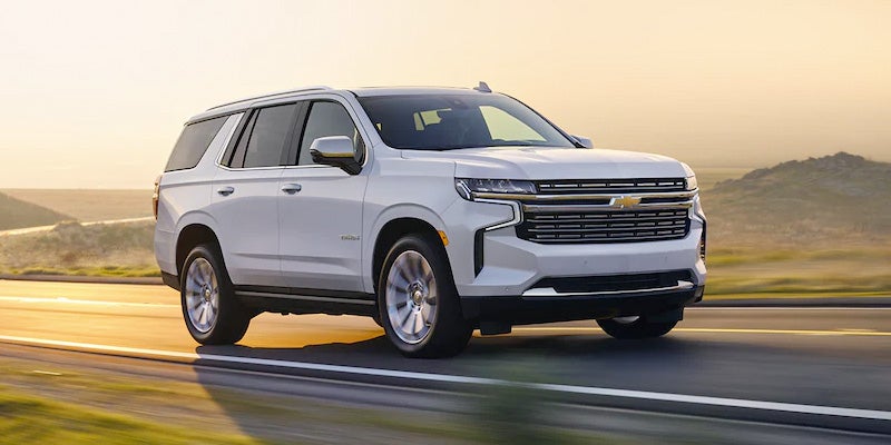 White SUV driving on a highway at sunset.