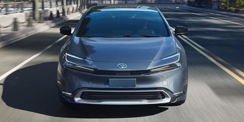 Front view of silver Toyota sedan driving on a city street.
