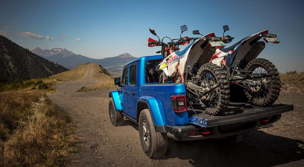 Rear of a blue 2026 Jeep Gladiator driving off-road.